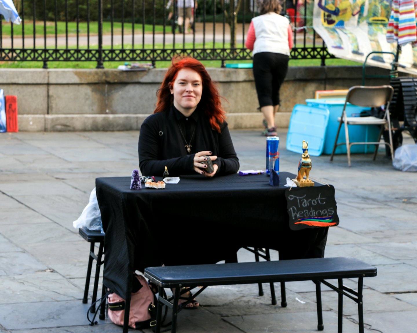 Woman sits at a tarot table with crystals and figurines.