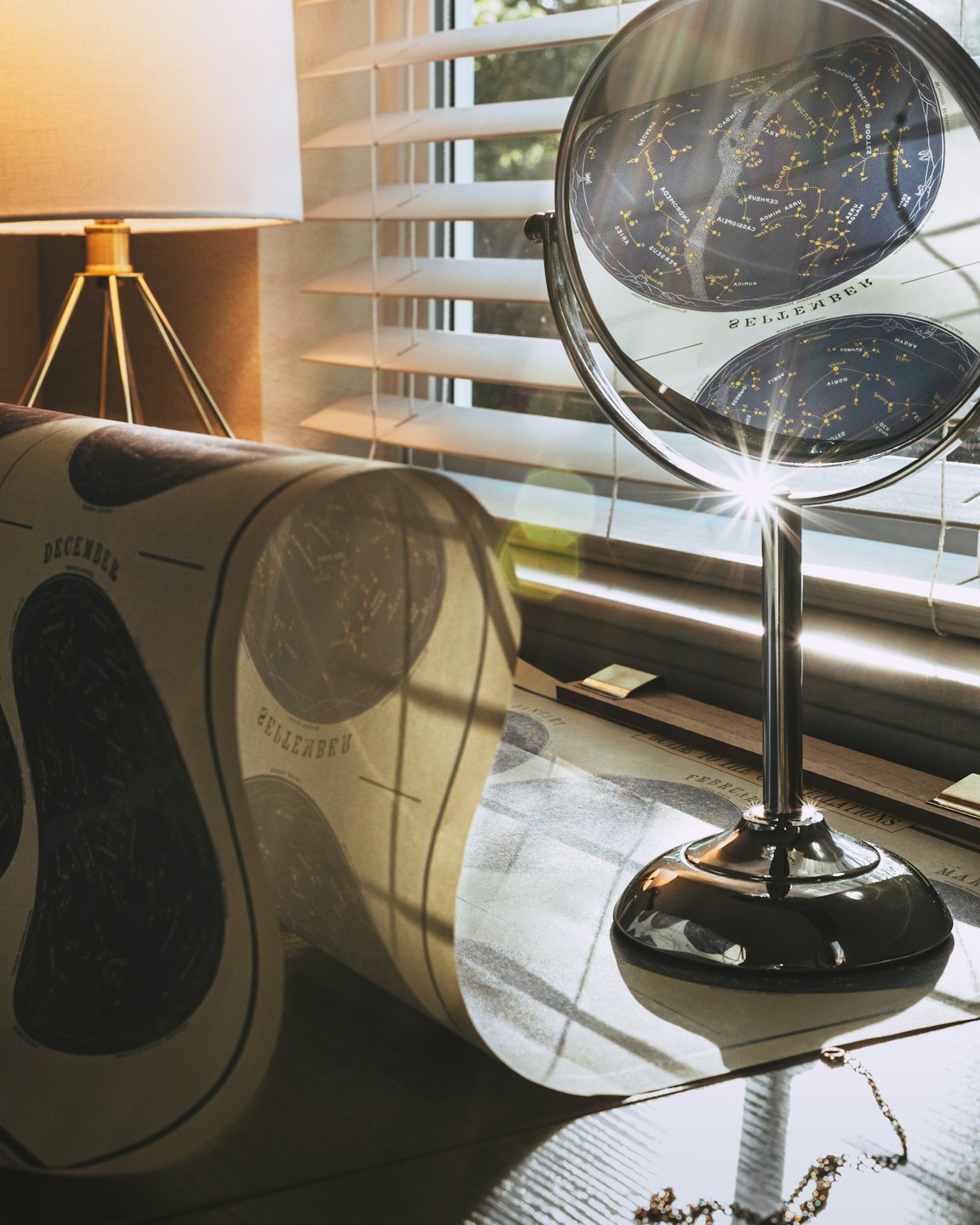 Celestial map unrolled on a wooden desk with a magnifying glass.